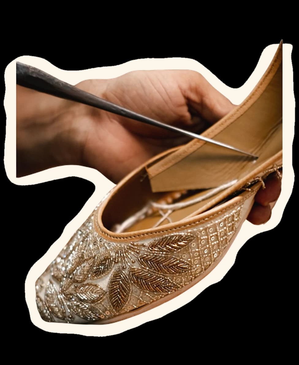 An artisan's hands finishing the sole of an embroidered jutti