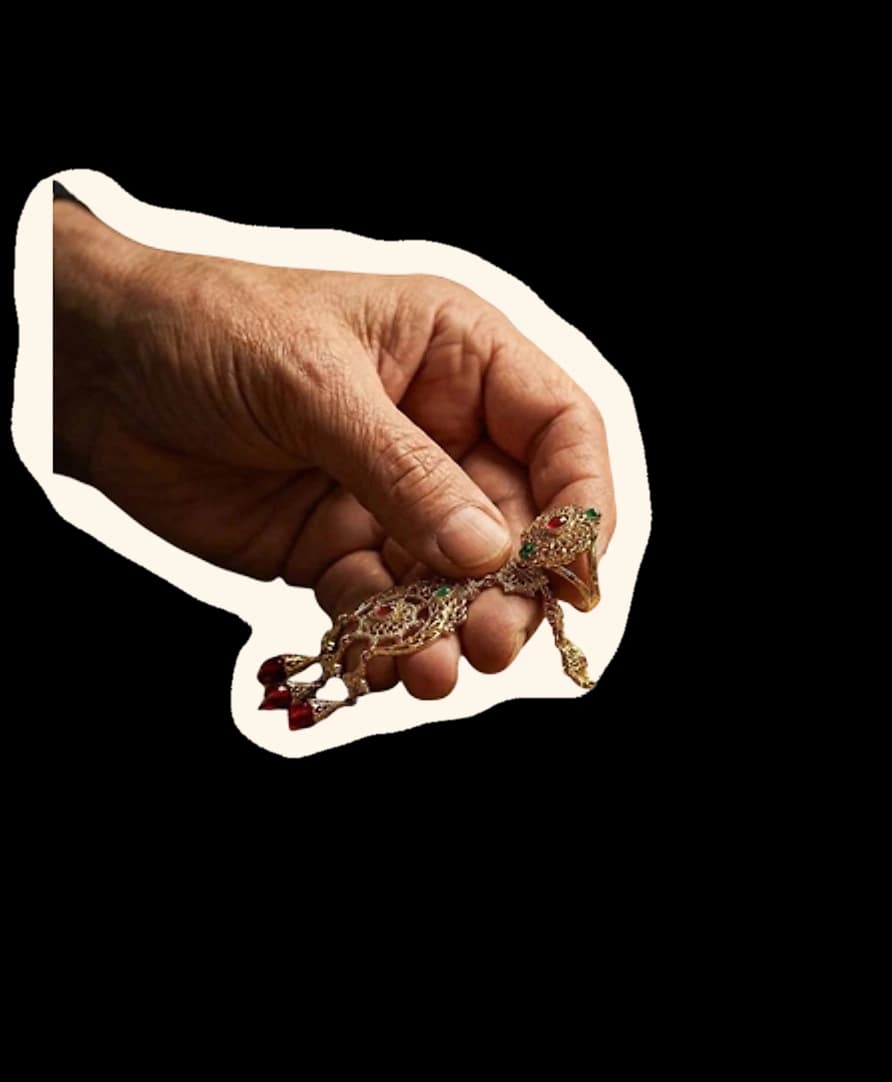 A hand holding a finished piece of Jaipuri jewellery